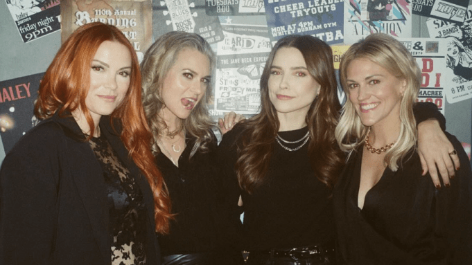 Danneel Ackles, Hilarie Burton, Sophia Bush and Bevin Prince pose in front of a wall of fliers